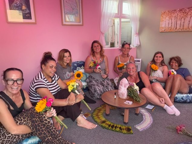 A group evening in the circle room, everyone sitting together with flowers